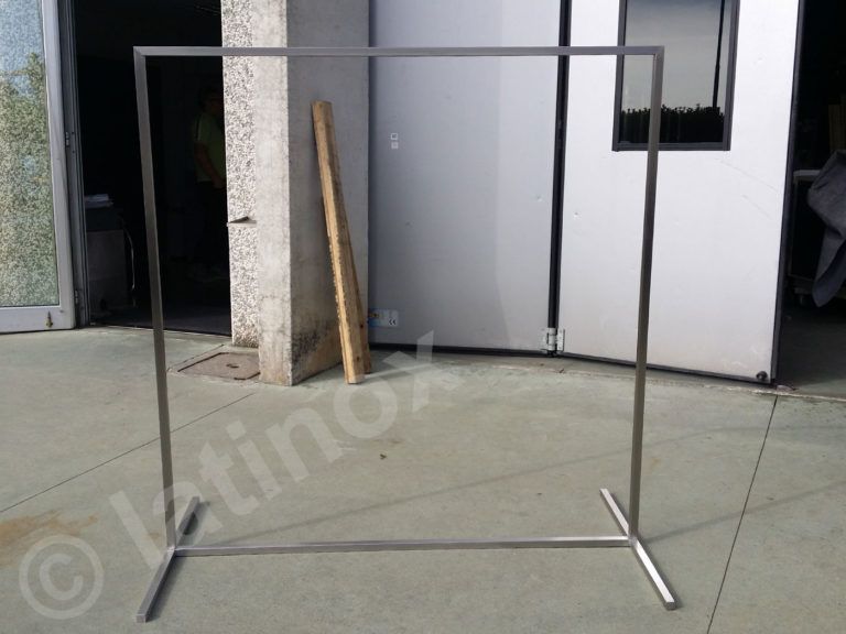 Espositore rettangolare in acciaio inox. Ambiente esterno con parete grigia e porta a vista.