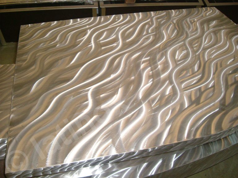 Pannello in metallo spazzolato con texture fluide e ondulate. Superficie riflettente e lucida.