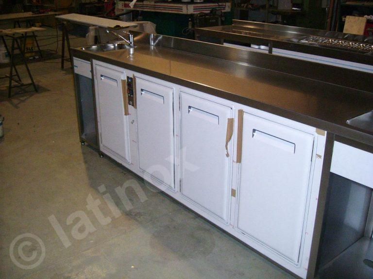Piano di lavoro in acciaio inossidabile con ante bianche e due rubinetti.