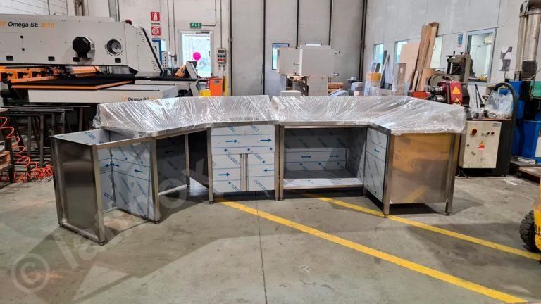 Isola da cucina in acciaio inox in un ambiente da laboratorio. L'unità è parzialmente avvolta in plastica.