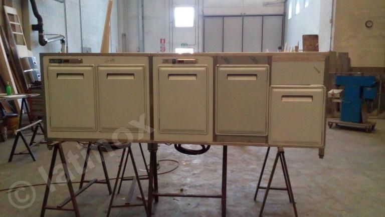 Mobiletto bianco sporco su cavalletti in un'officina. Contiene diverse ante/cassetti di varie dimensioni.