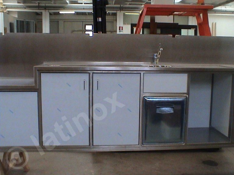 Cucina esterna in acciaio inox con lavello, mobili e piccolo frigorifero.