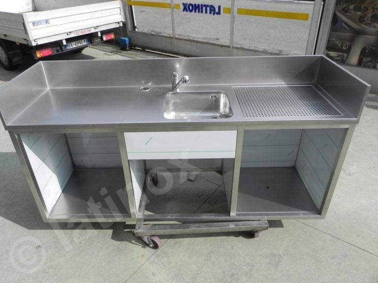 Lavello da cucina commerciale in acciaio inox con scolapiatti, rubinetto e vano portaoggetti aperto.