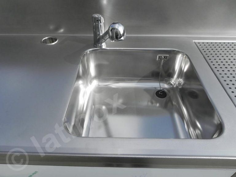 Lavello in acciaio inox con rubinetto e scolapiatti integrati nel piano di lavoro.