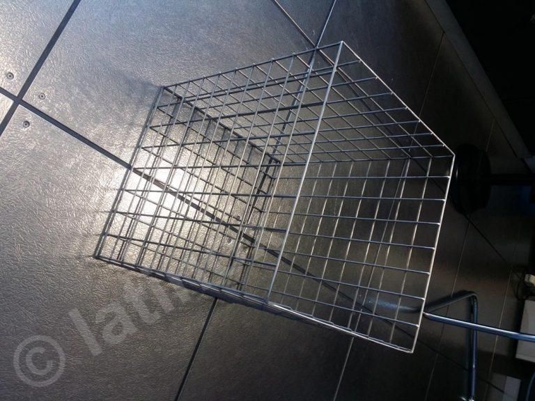 Cestino di cubi di filo metallico su una superficie scura piastrellata.