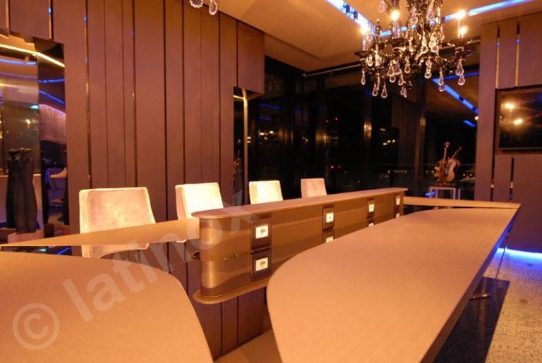 Moderna sala riunioni con lungo tavolo, sedie bianche, lampadario e vista notturna dalla finestra.