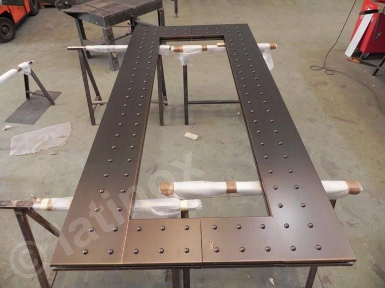 Telaio in metallo con numerose caratteristiche simili a rivetti distanziati in modo uniforme, appoggiato su cavalletti in un'officina.