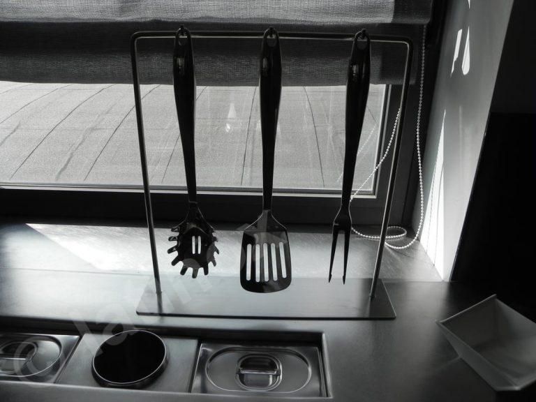 Utensili da cucina appesi a una rastrelliera di metallo vicino a una finestra.