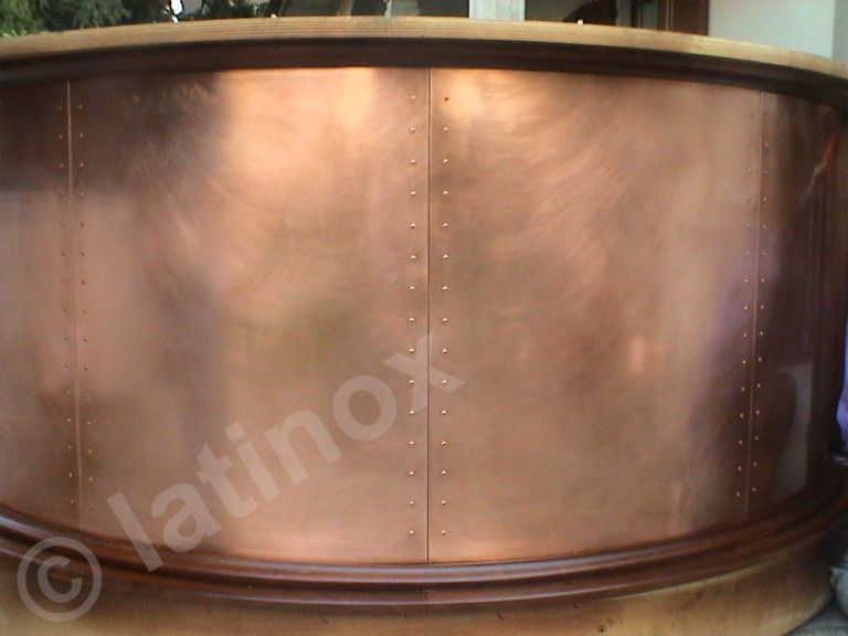 Facciata in barre di rame con finiture in legno. Pannelli di rame rivettati creano una struttura curva.