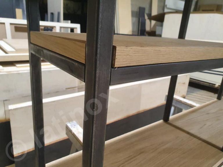 Primo piano di una mensola in metallo e legno. La struttura è scura e i ripiani sono in legno chiaro.