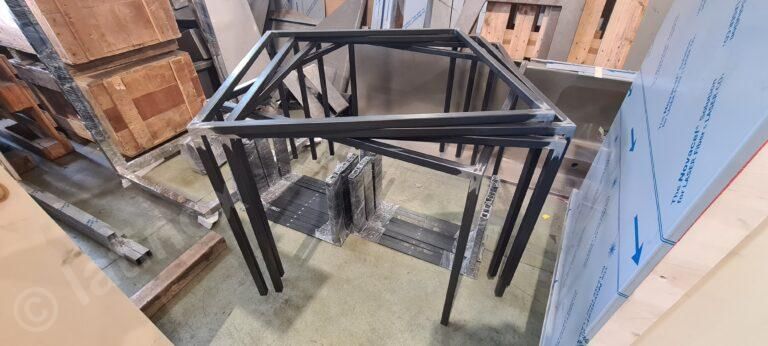 Struttura del tavolo in metallo nero in un magazzino con casse di legno e lamiere.