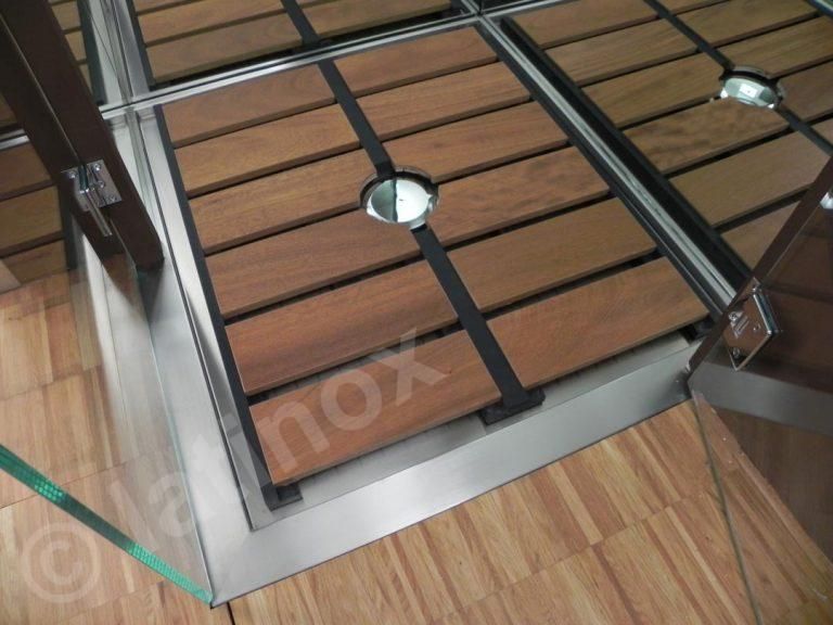 Espositore da terra in legno con struttura in acciaio inox e divisorio in vetro.