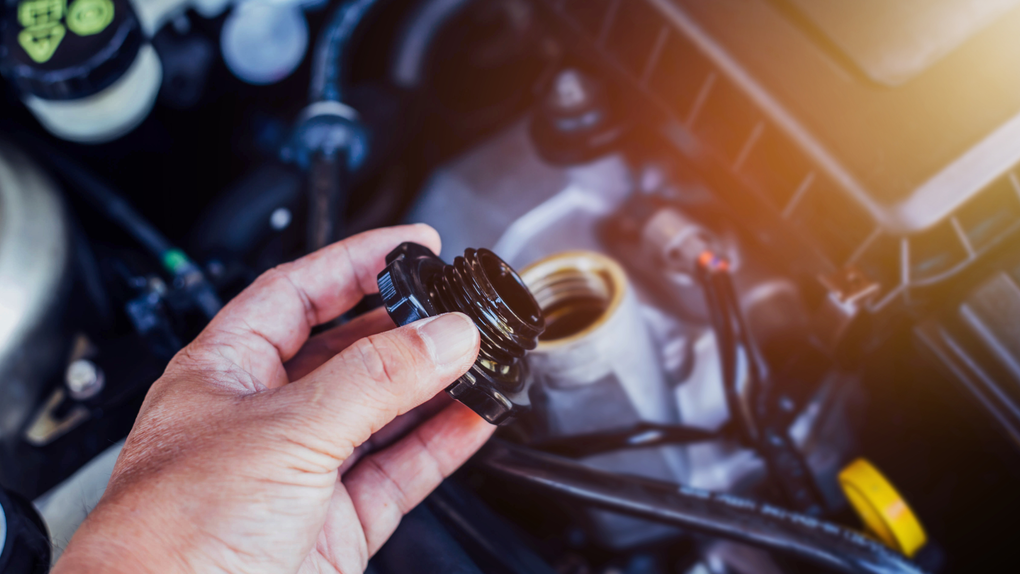 A person is pouring oil into a car engine.