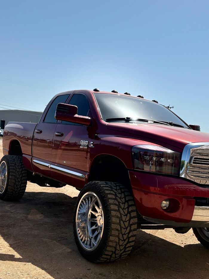 A red truck is parked on a dirt road.