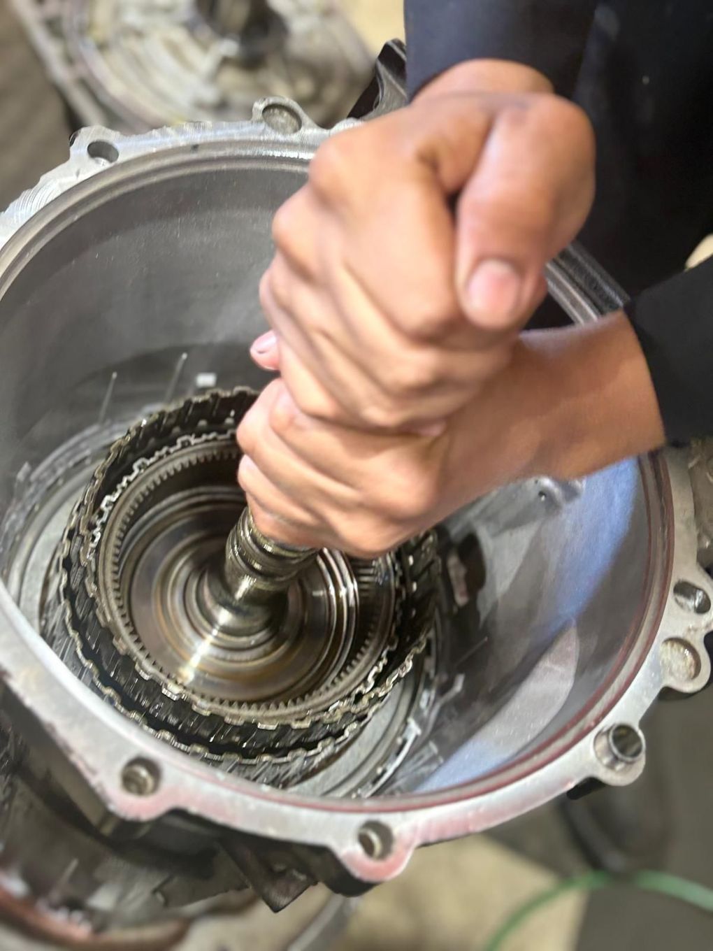 A person is working on a gearbox with their hands
