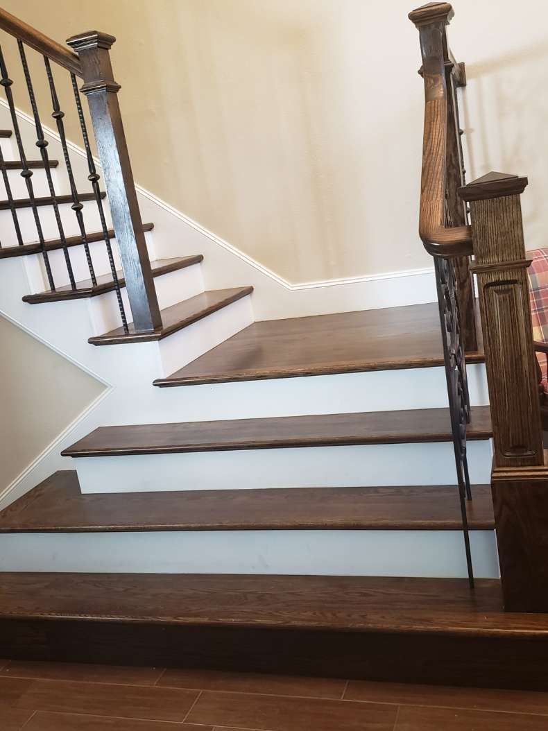 A wooden staircase with dark-stained steps and white risers, featuring a decorative railing and posts.