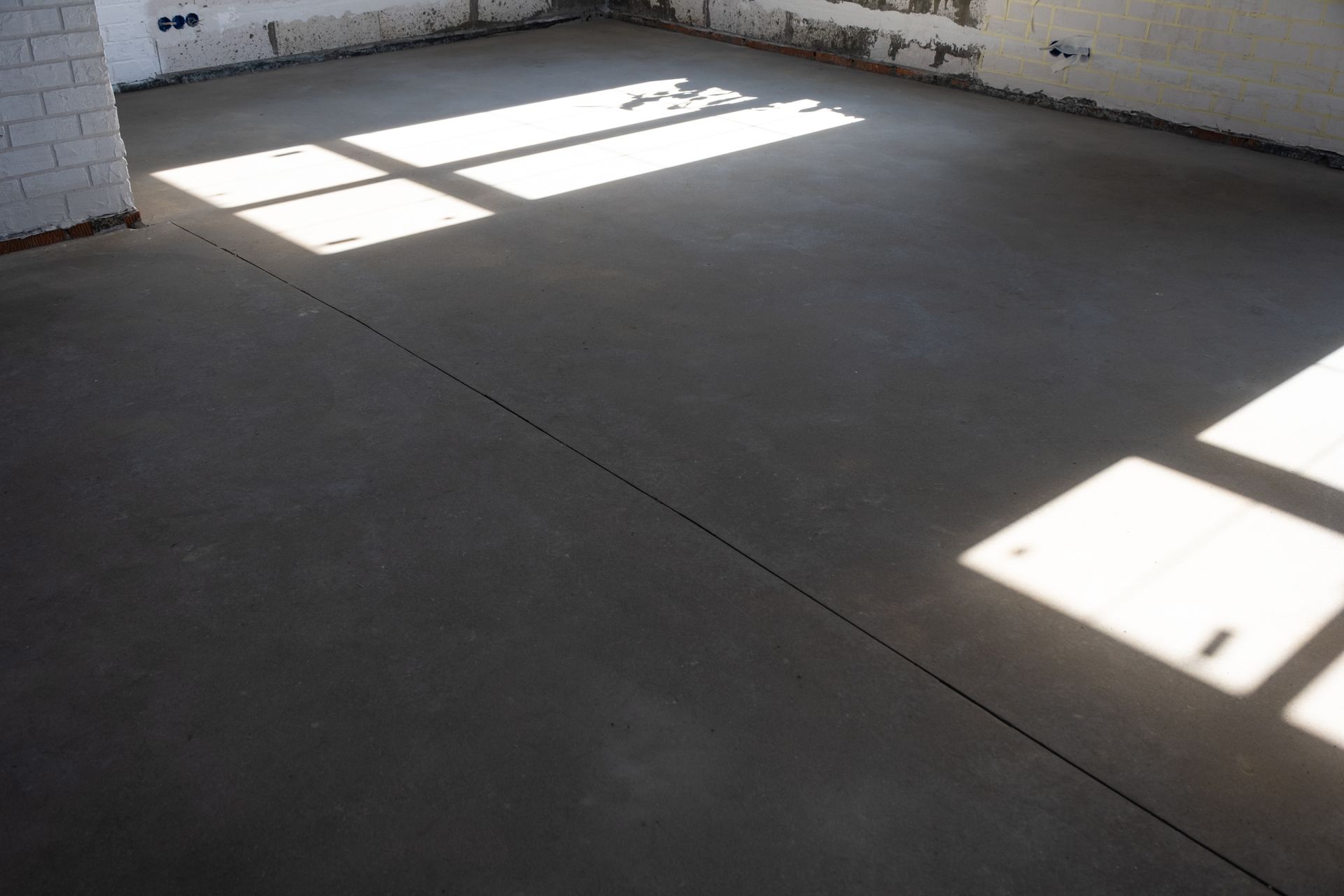 Concrete floor in a room with sunlight shadows from a window.