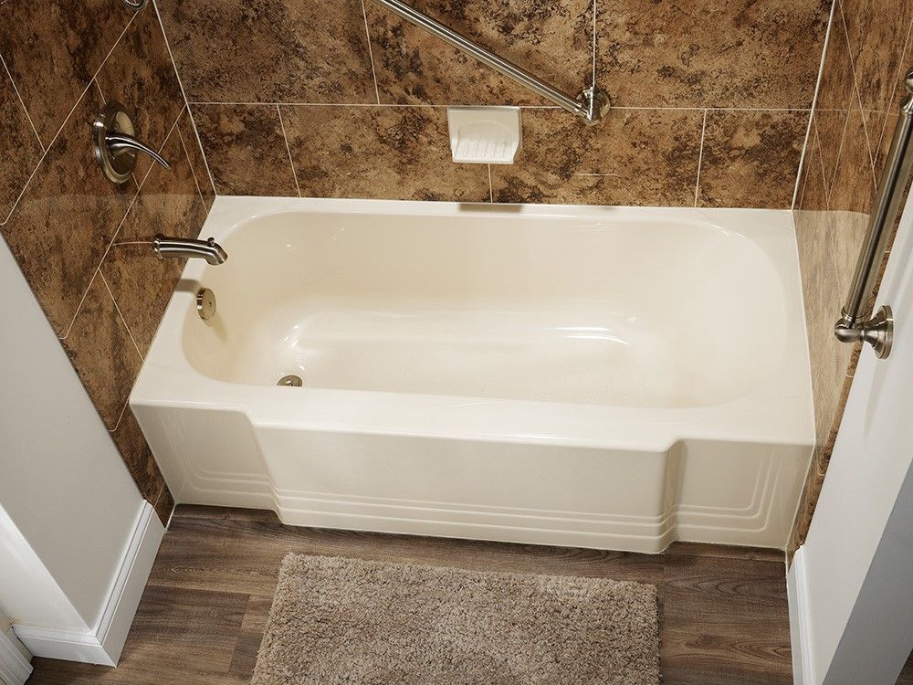 A bathtub with a handle on the side of it in a bathroom.