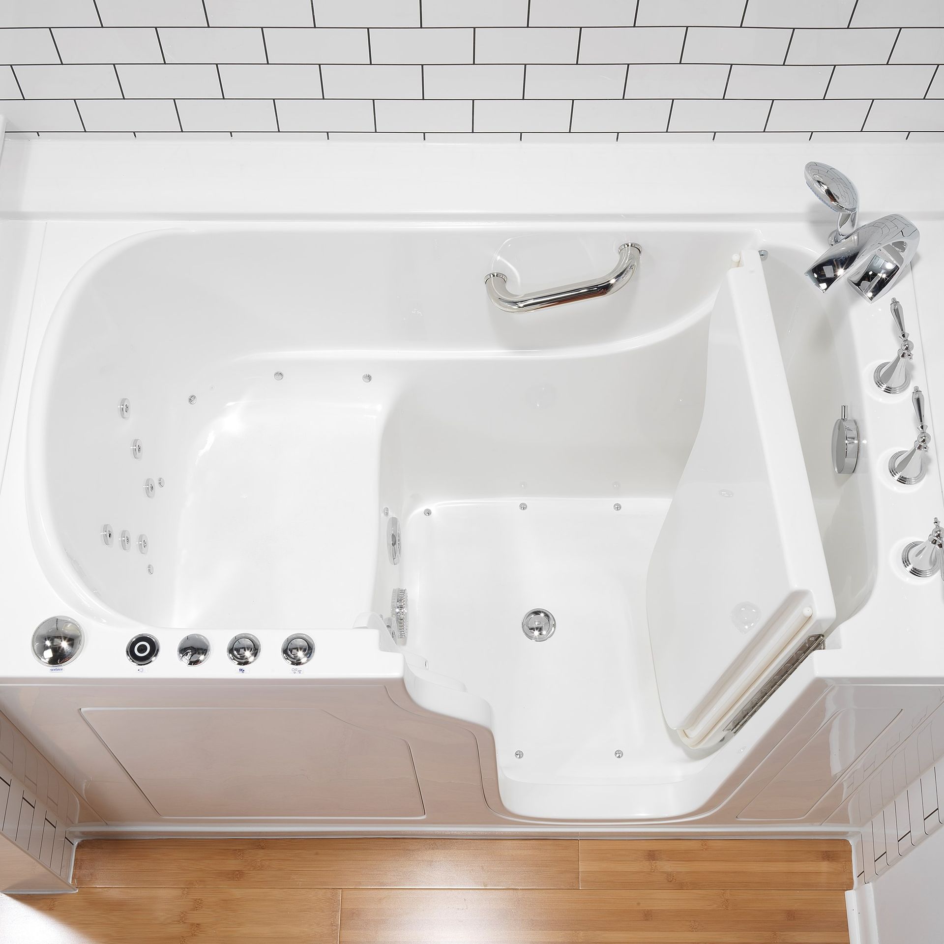 White walk-in bathtub with open door, chrome fixtures, grab bar, and jets; set against white tile.