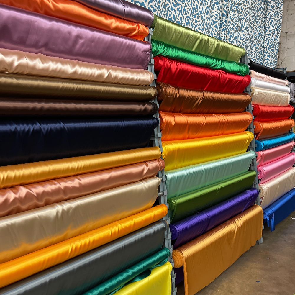 Stacks of colorful satin fabric rolls in a store.