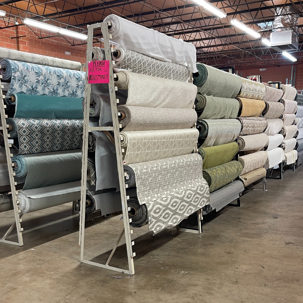 Shelves stacked with fabric rolls in various patterns and colors inside a store.