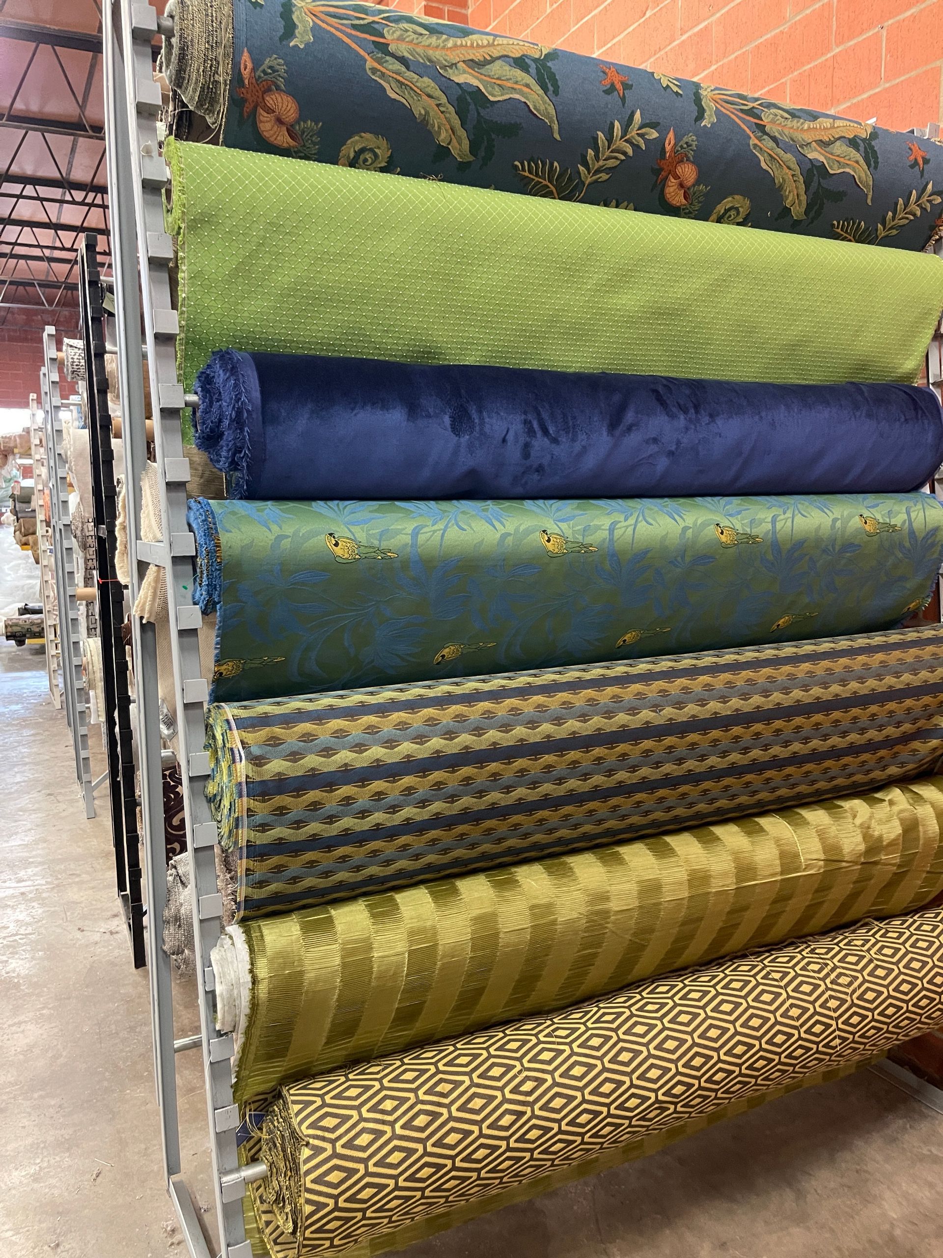 Shelves holding rolls of colorful fabric; blues, greens, patterned, and solid.