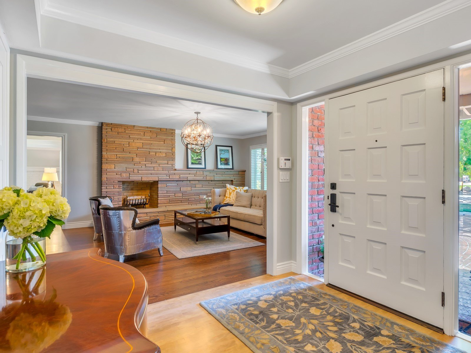 Entryway with open door, leading to a living room with fireplace and seating. Andrea Lim | Practical Vanity Interiors | Granite Bay, CA | Interior Design