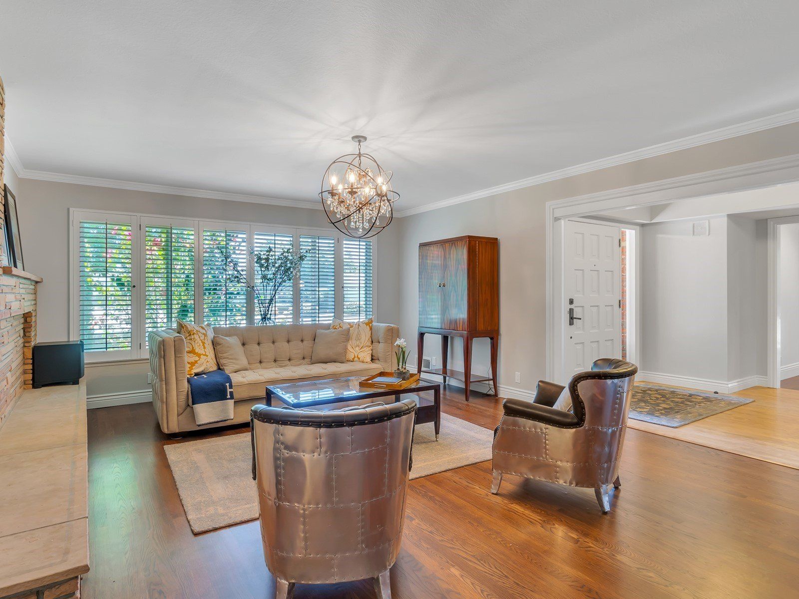 Living room with tufted sofa, metal chairs, wood floors, and chandelier. Andrea Lim | Practical Vanity Interiors | Granite Bay, CA | Interior Design