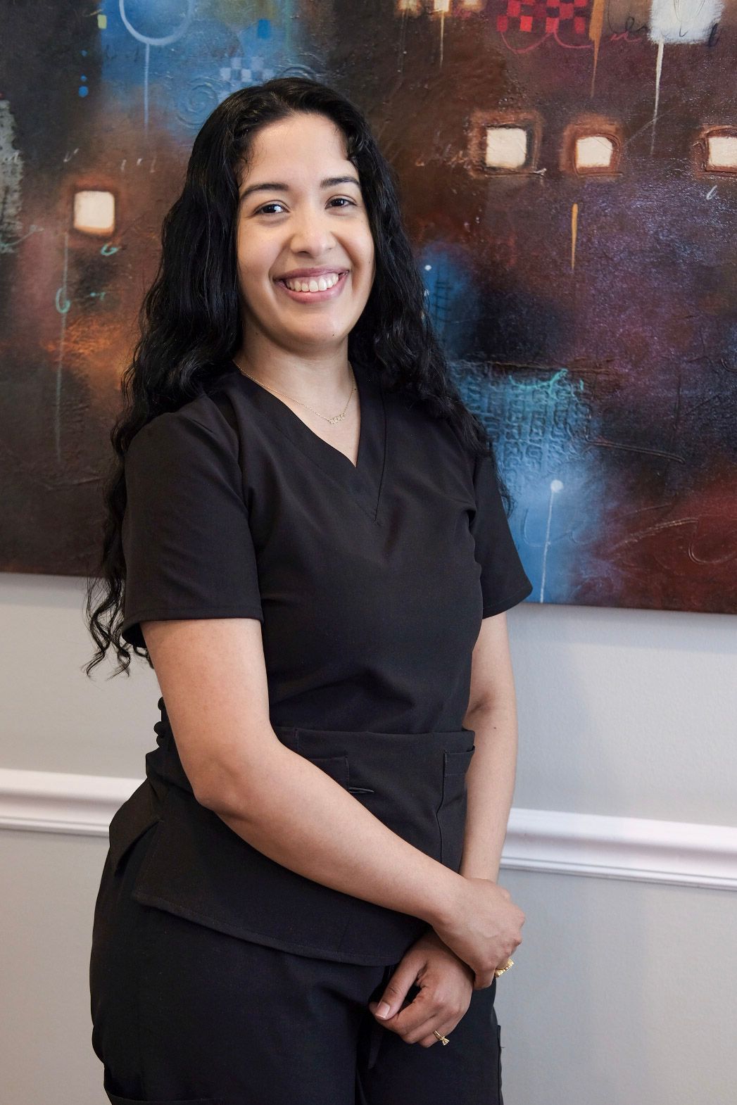 A woman in a black scrub top is smiling for the camera.