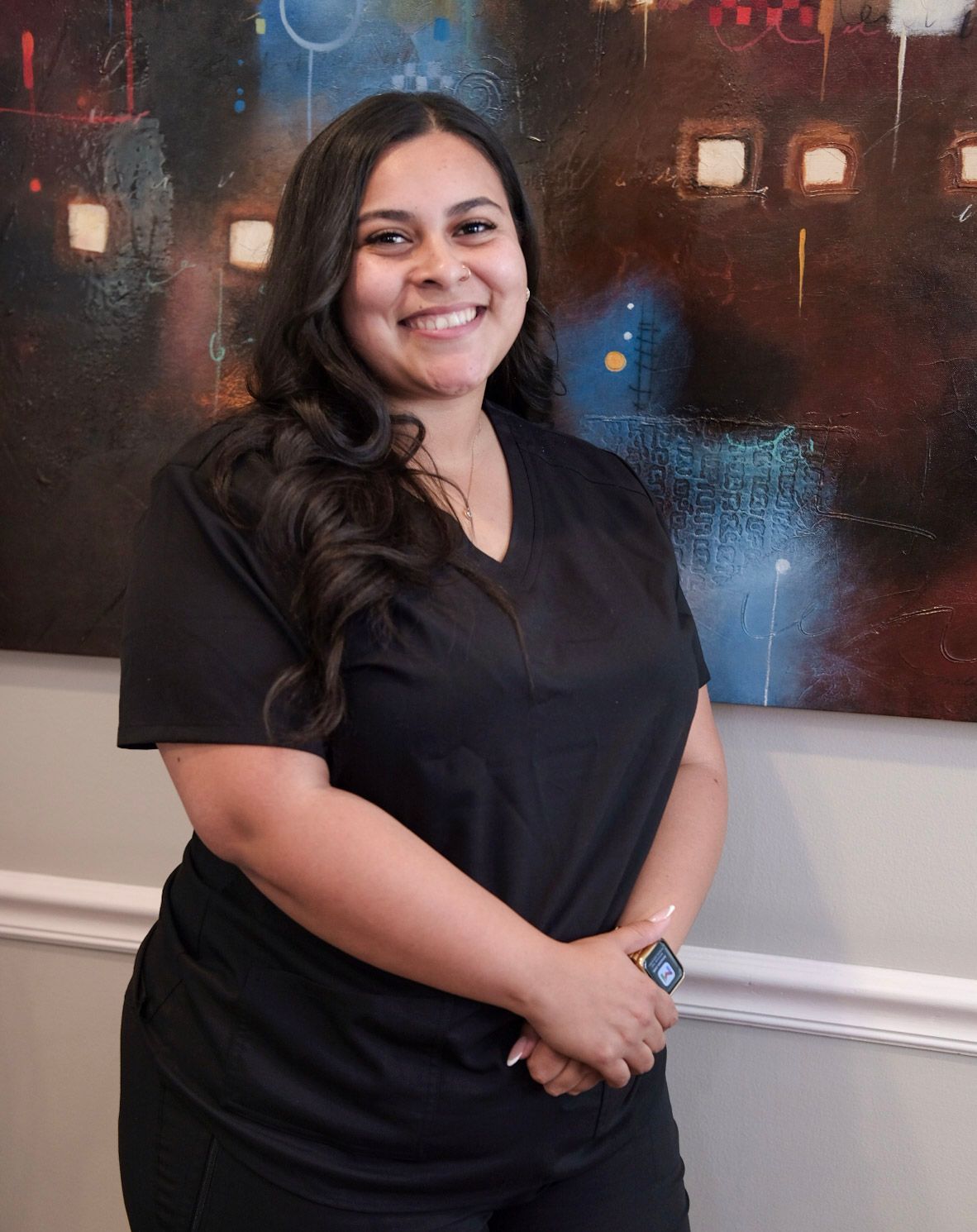 A woman with long hair is wearing a black shirt and smiling for the camera.
