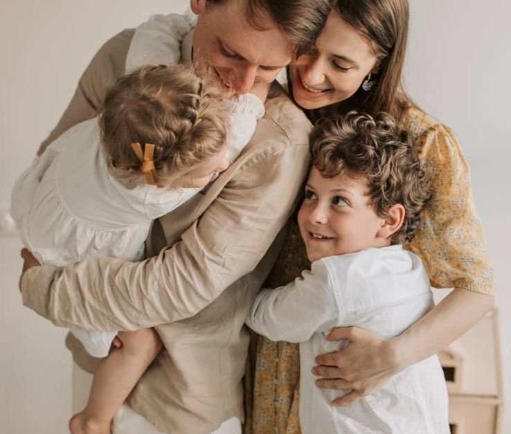 A family is hugging each other on a bed.