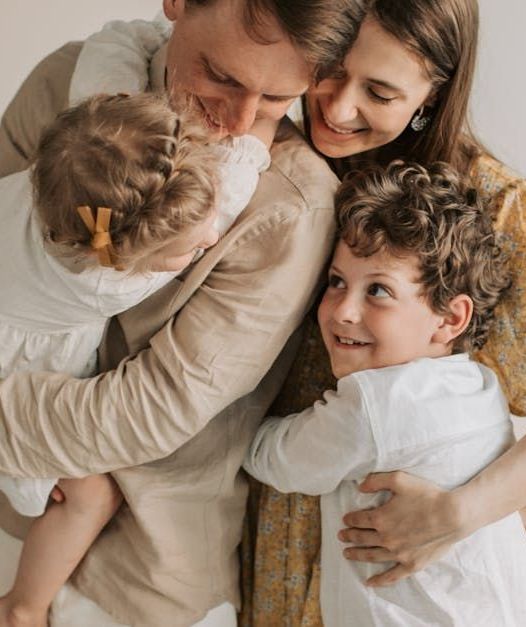 A family is hugging each other on a bed.