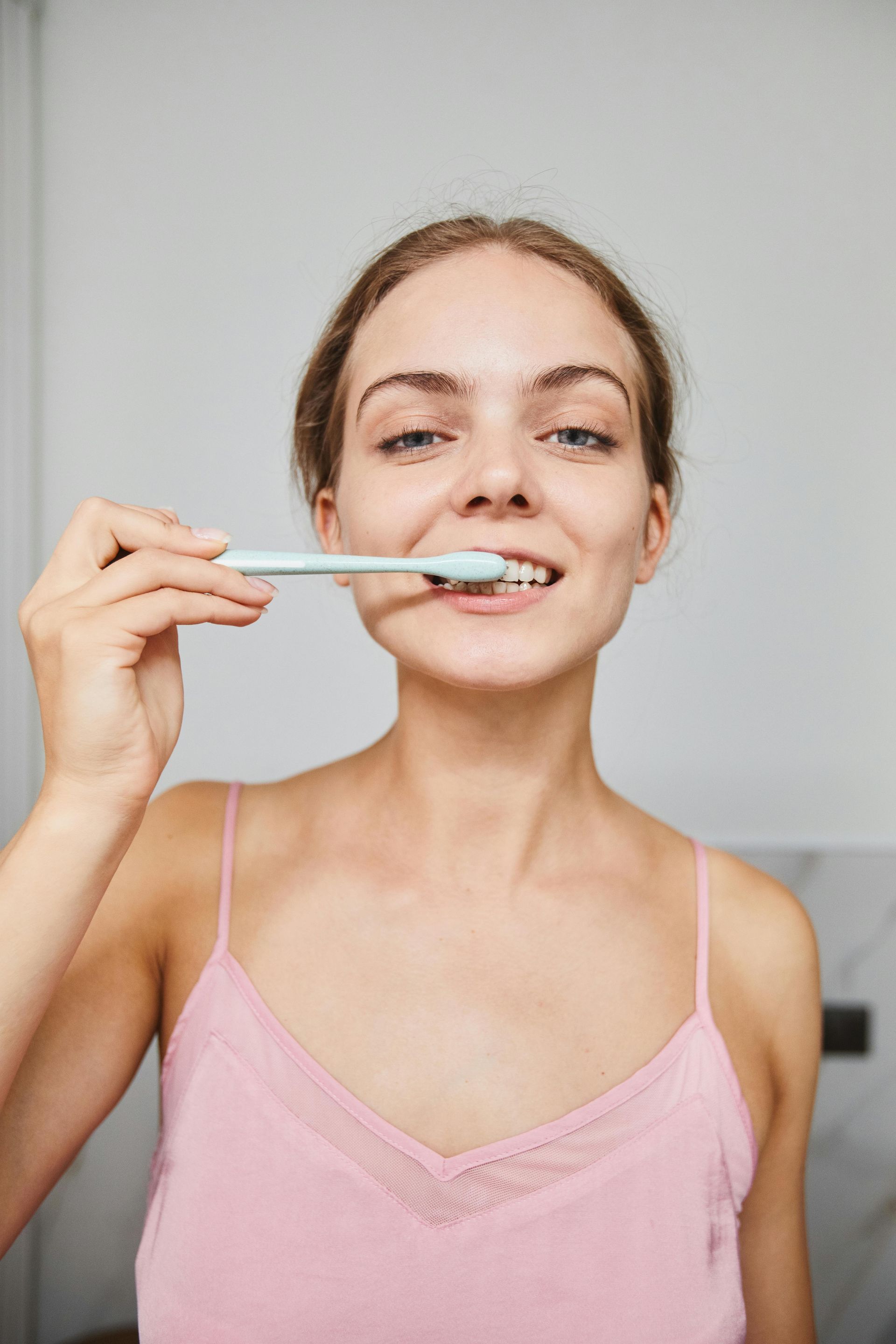 A woman is brushing her teeth in front of a mirror.