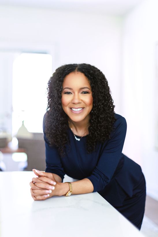 A woman in a blue dress leaning again a counter.