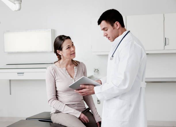 A doctor is talking to a patient who is sitting in an examination chair.