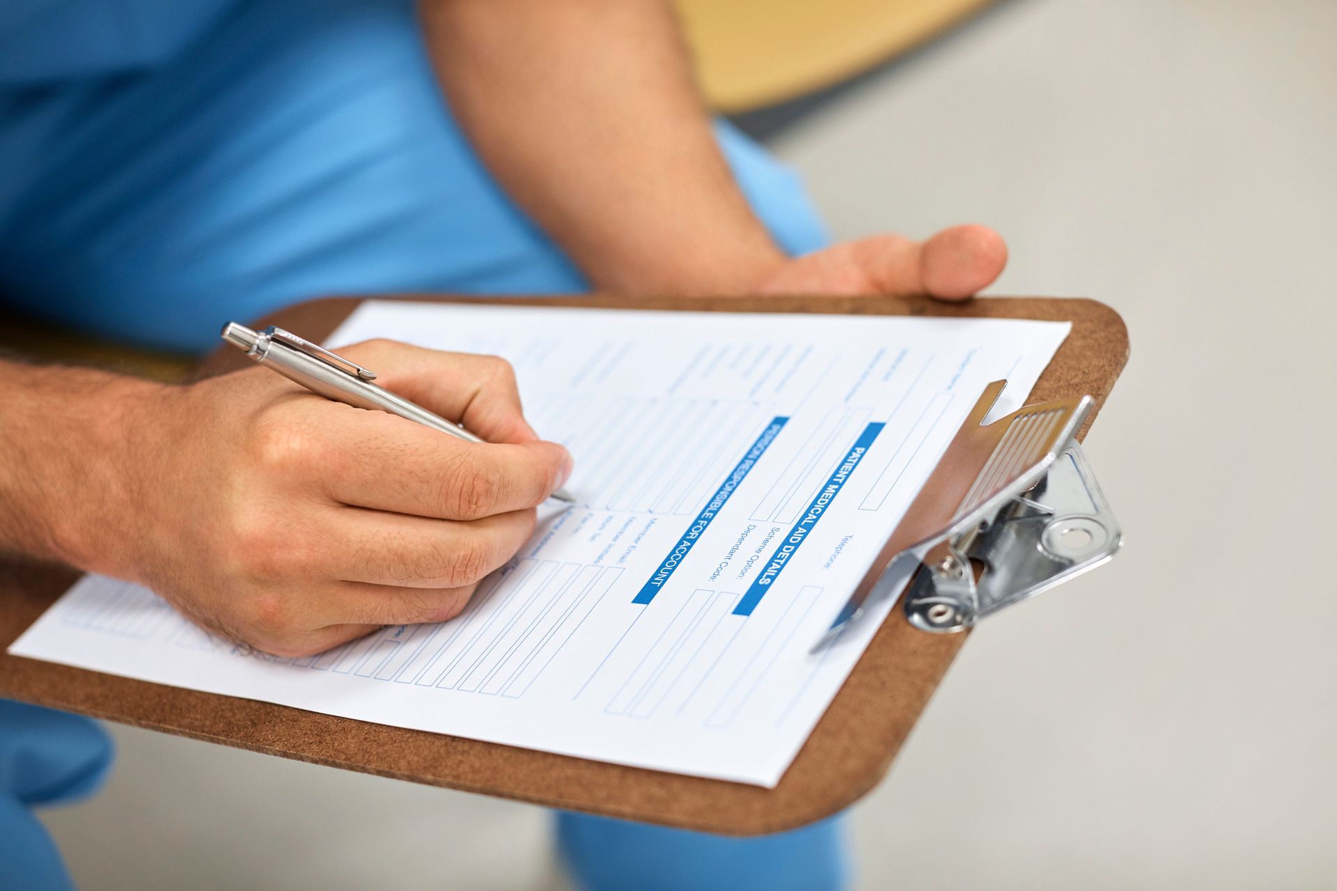 A person is writing on a clipboard with a pen.