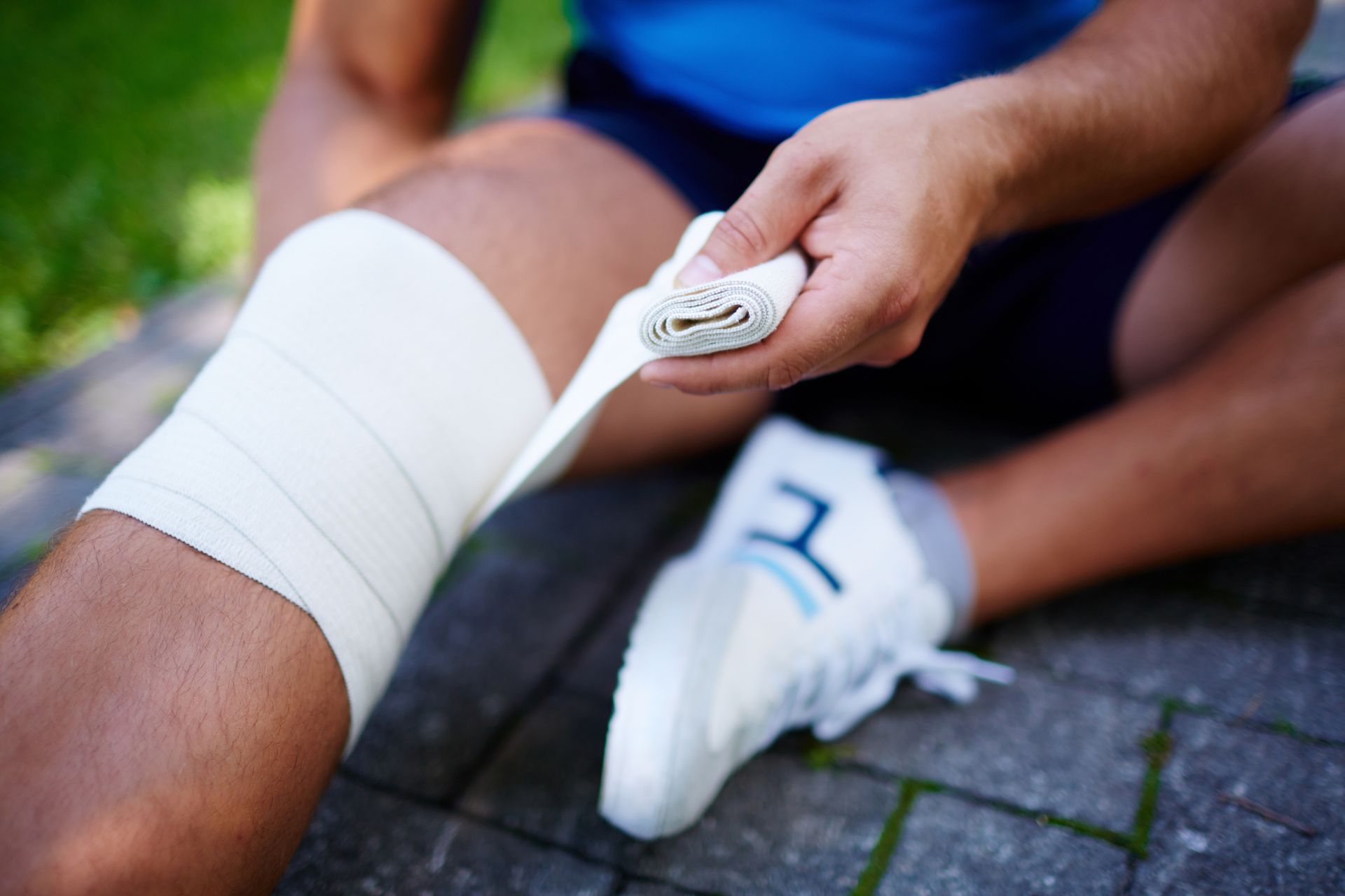 A person is wrapping their knee with a bandage.