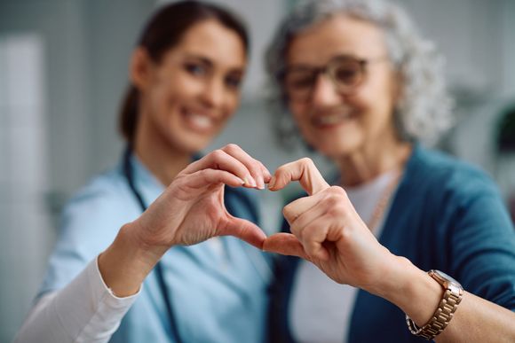 Caregiver and senior woman forming a heart shape together at Clearstream Rehab