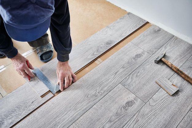 Picture of worker installing in wood flooring with a measurer 