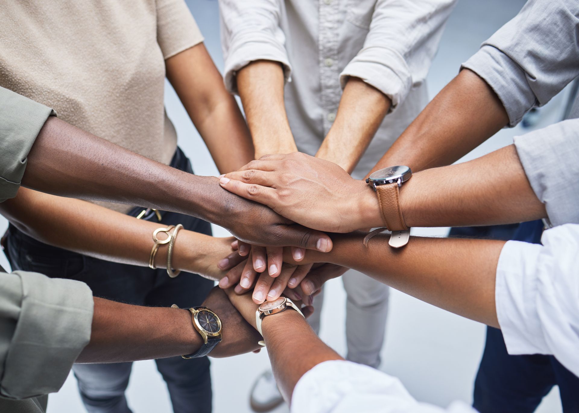 Diverse hands stacked together in a circle, symbolizing unity and teamwork.