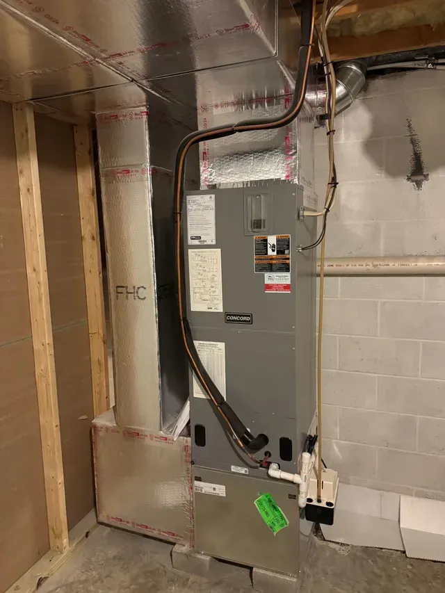 HVAC system in a basement with insulated ductwork. Gray unit against a wall.