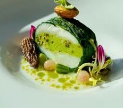 Bol en bois contenant un plat culinaire fumé à la glace carbonique, avec des herbes, des fruits de mer et des glaçons d'orange.