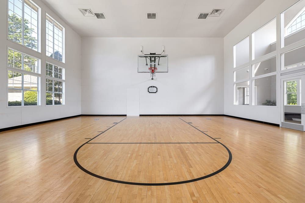 an empty basketball court with a wooden floor and a basketball hoop on the wall at The Preserve at Ballantyne Commons in Charlotte, NC.