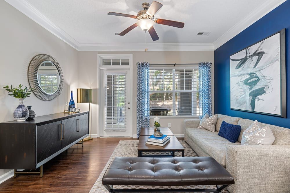 a living room with a couch , coffee table , mirror and ceiling fan at The Preserve at Ballantyne Commons in Charlotte, NC.