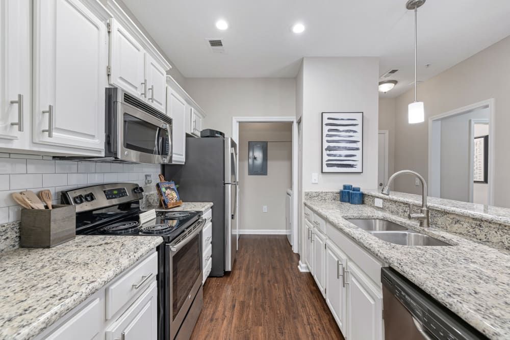 a kitchen with granite counter tops , stainless steel appliances , and white cabinets at The Preserve at Ballantyne Commons in Charlotte, NC.