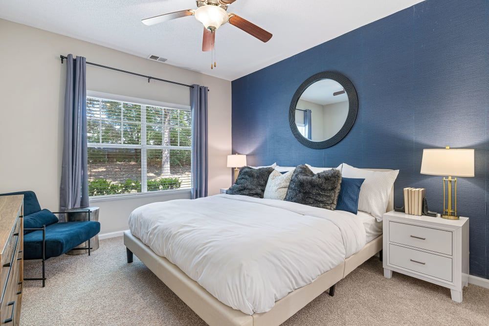 a bedroom with a king size bed , nightstand , chair and ceiling fan at The Preserve at Ballantyne Commons in Charlotte, NC.