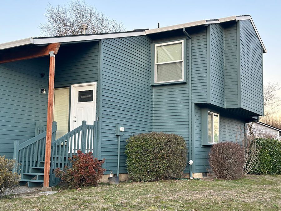 A blue house with stairs leading up to the front door