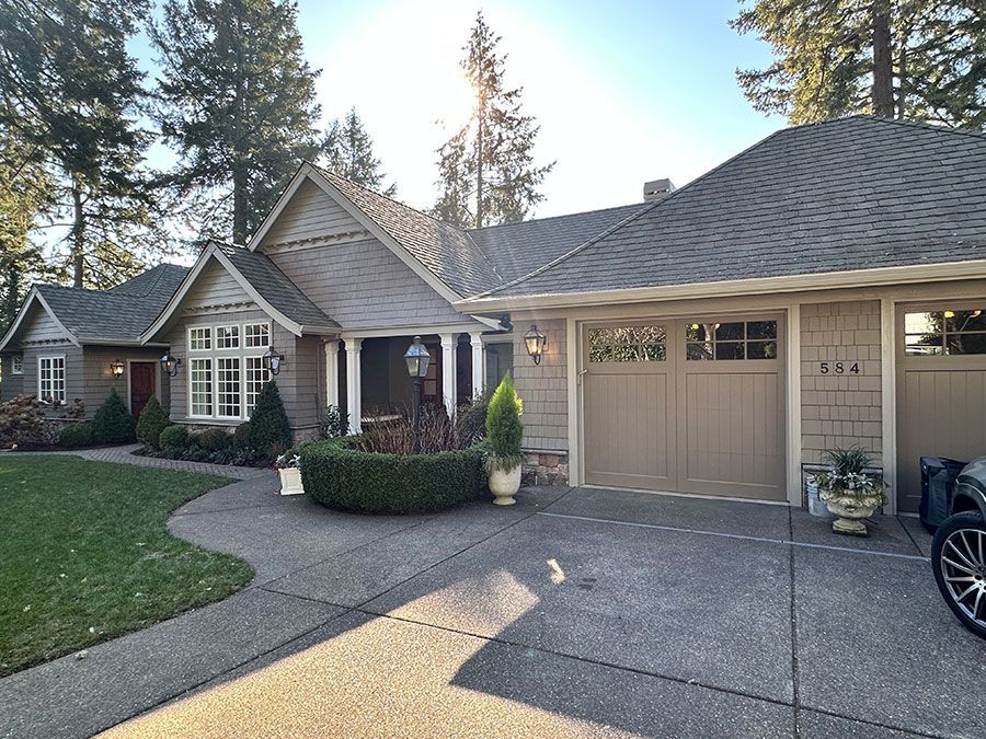 A large house with two garage doors and a bicycle parked in front of it.