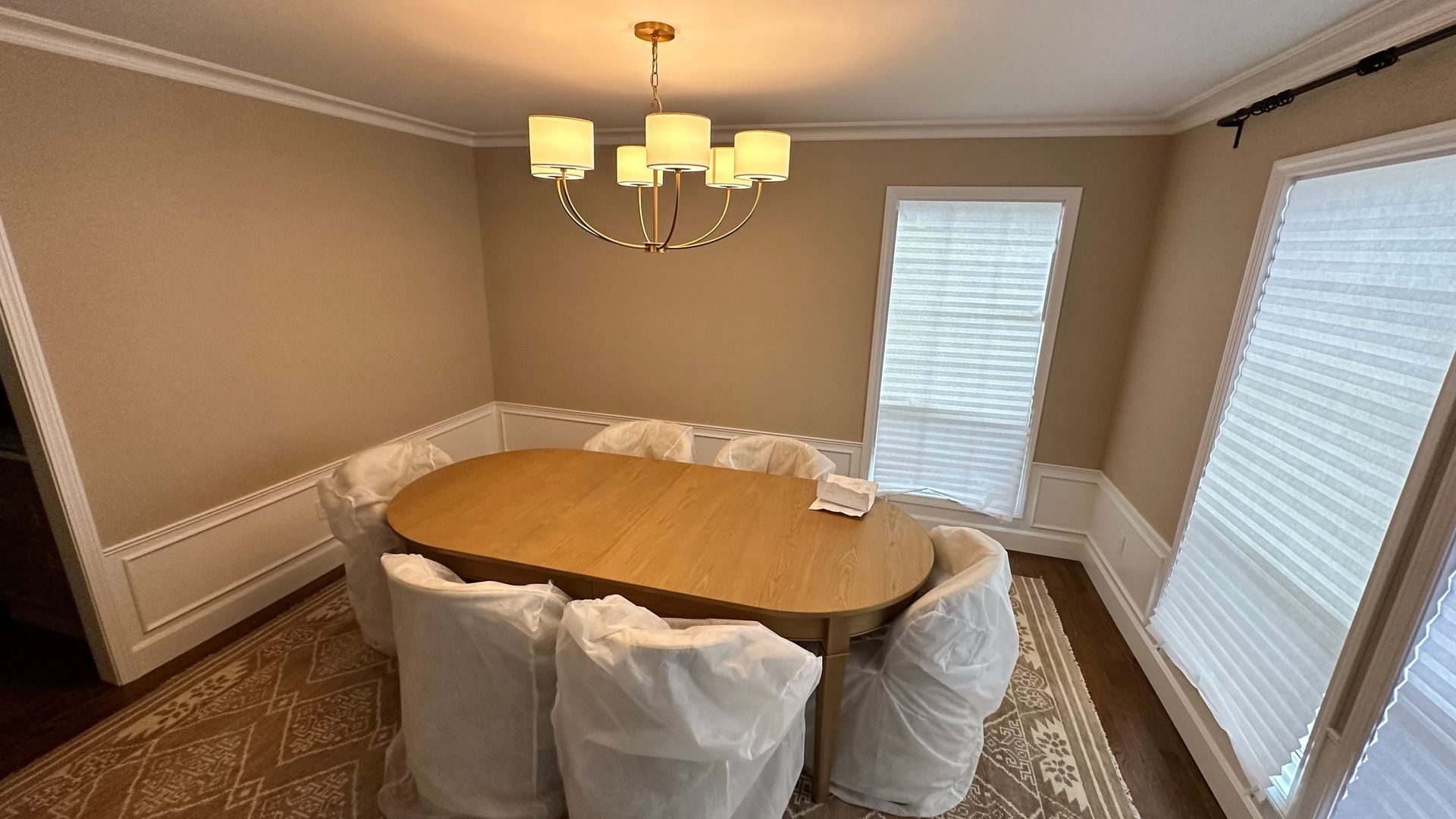 A dining room with a table and chairs wrapped in plastic.