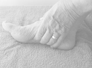 Elderly woman massaging her foot